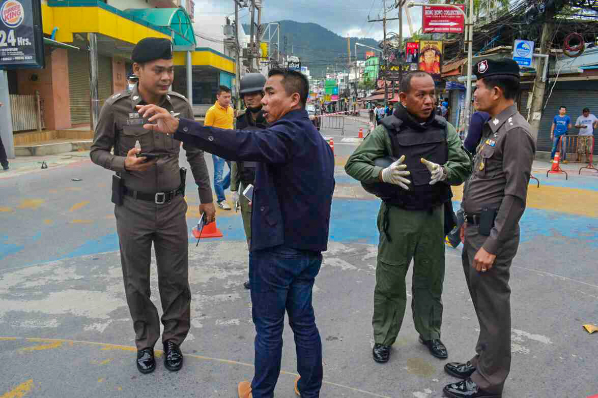 Security officers on Friday inspect the scene of bomb attack on Phuket, where an unexploded firebomb was found two days earlier.