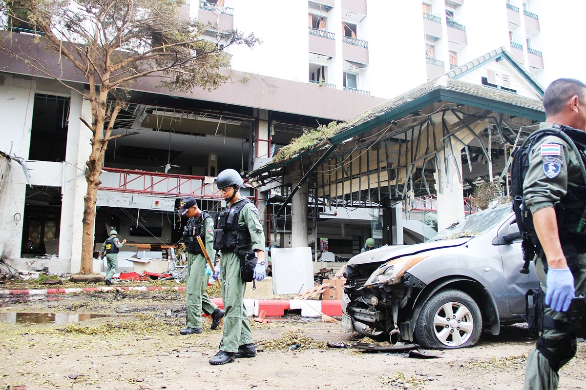 Police officers on Wedneday morning inspect the site of the deadly twin car bomb that struck a hotel in Pattani province.