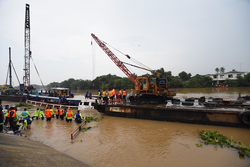 Officers salvage a partially submerged boat Tuesday afternoon from the Chao Phraya River in Ayutthaya province.