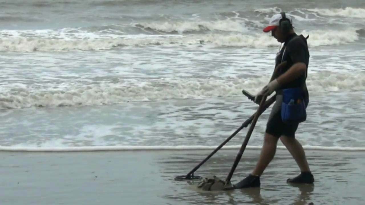 An unnamed foreigner later identified as Stefan Burford combs Pak Meng Beach with a heavy-duty metal detector Thursday morning in Trang province.