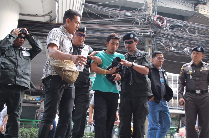 Niheng Yeening, 27, one of six suspects charged Tuesday, is taken for a police “reenactment” at Big C Ramkhamhaeng.