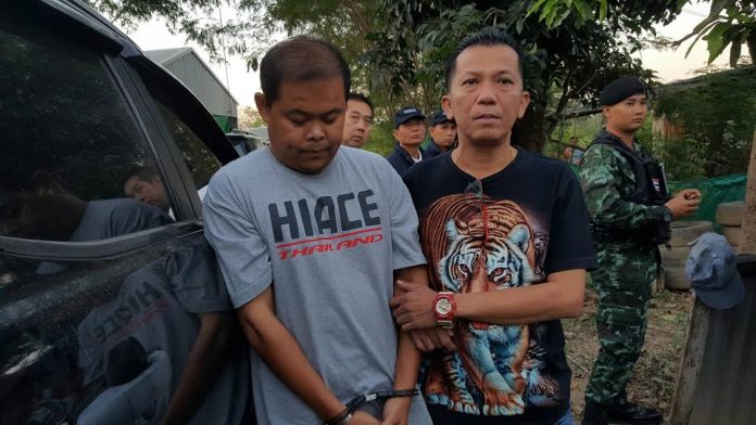 Police with one of seven alleged fraud and lese majeste suspects accused of crashing weddings and funerals to demand money in exchange for gifts.