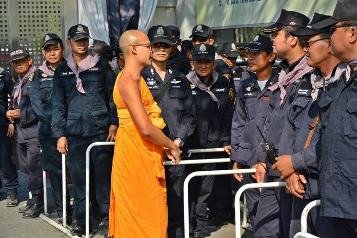 Monk talks to police outside Wat Dhammakaya on Thursday.