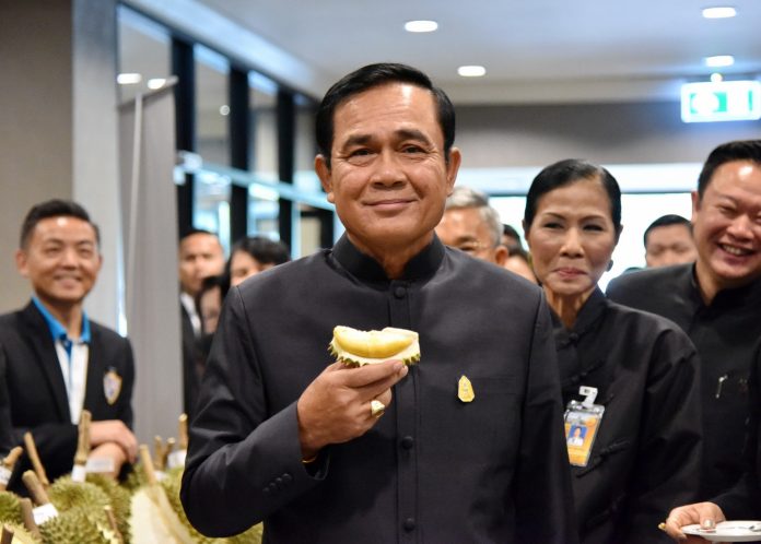 Gen. Prayuth Chan-ocha smiles with a Durian wedge at a presentation of seasonal fruit on June 9 at Government House.