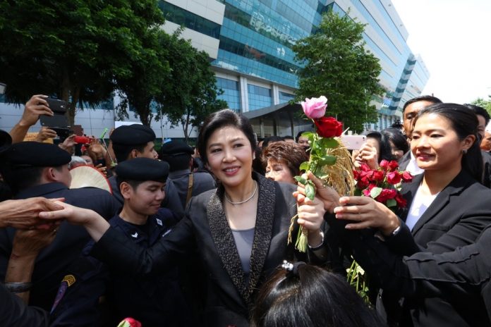 Former premier Yingluck Shinawatra accepts flowers from her supporters Friday outside the Supreme Court in Bangkok.