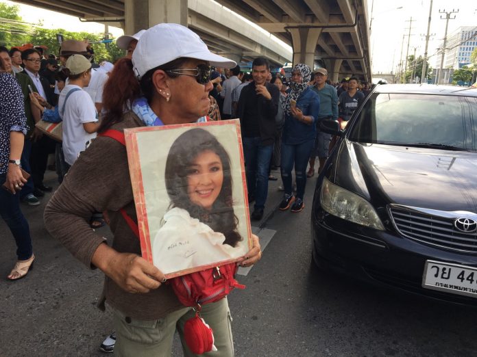 A supporter of former PM Yingluck Shinawatra holds a portrait of her Friday near the Supreme Court.