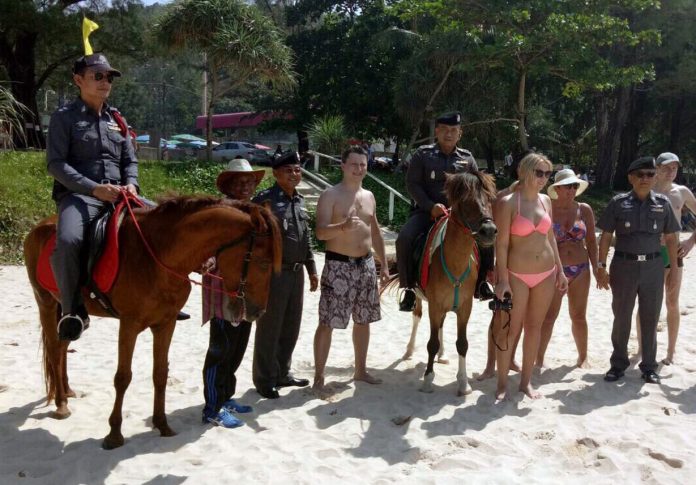 Horseback patrol police pose for photos with tourists on Surin Beach in Phuket province Dec. 9, 2016