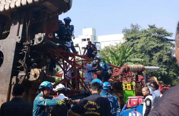 Emergency officials pull Somphong Kaewduangjan, 54, from a fallen crane Friday morning at Khlong Bang Sue.