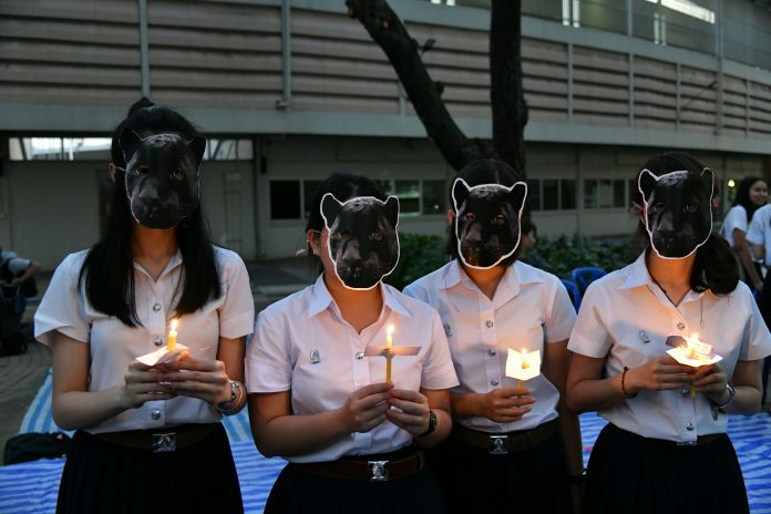 Chulalongkorn students on Tuesday evening wear black panther masks and hold candles to mourn killed animals at the Thungyai Naresuan Wildlife Sanctuary.
