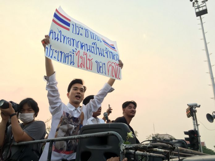 Karn Pongpraphapan holds a sign atop a truck carrying pro-democracy leaders on a march through Bangkok on March 24.