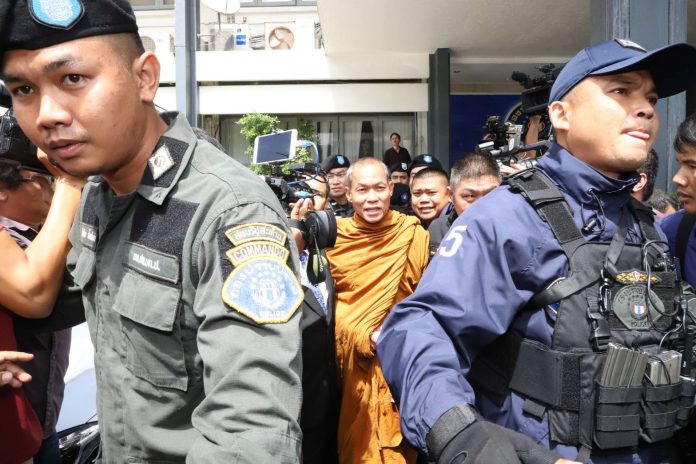 Police escort Buddha Issara to a court on Thursday