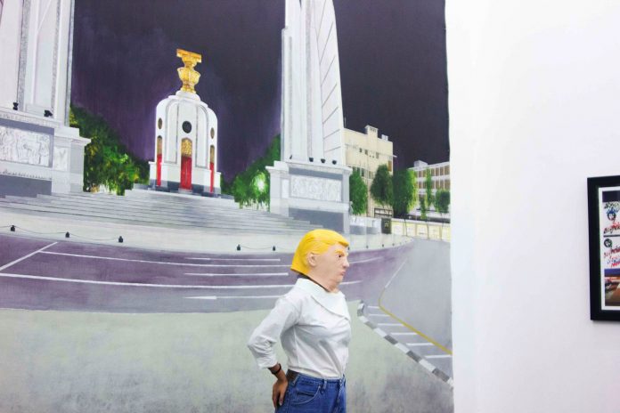 A visitor wears a Donald Trump’s mask at an art installation by Guerrilla Boys in 2017 at Cartel Artspace in Bangkok. Photo: Bangkok Biennial / Courtesy