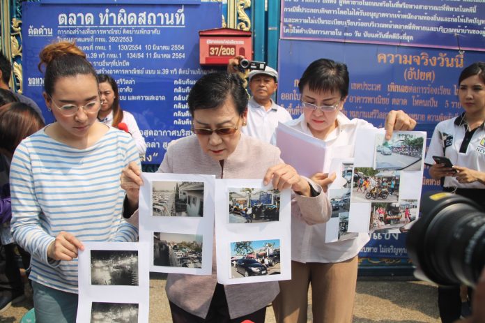 Boonsri Saengyoktrakarn and her family hold up photos of people parking illegally in front of their house.