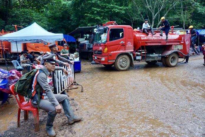 Officers and rescue workers stay put among momentary calm early Tuesday evening near the Luang Cave complex in Chiang Rai province.