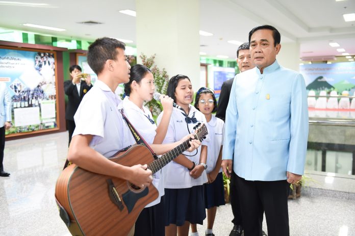 Junta chairman Prayuth Chan-ocha poses for photos Thursday with a group of young musicians in Bangkok.