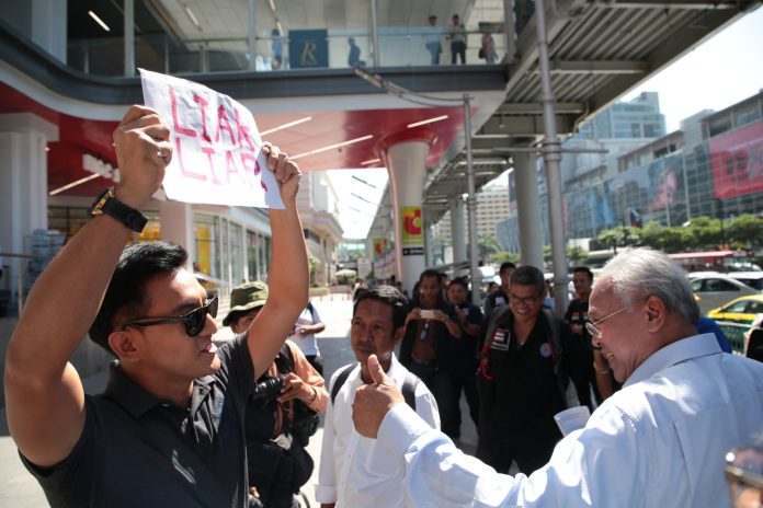 Akawutt 'Ake' Auttagorn holds a sign reading 'Liar Liar' as Suthep Thaugsuban canvasses Wednesday at Big C Ratchadamri. Akawutt 'Ake' Auttagorn holds a sign reading 'Liar Liar' as Suthep Thaugsuban canvasses Wednesday at Big C Ratchadamri.