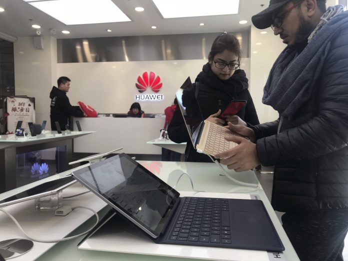 Foreigners look at a Huawei computer at a Huawei store in Beijing, China, Thursday, Dec. 6, 2018. (AP Photo/Ng Han Guan)