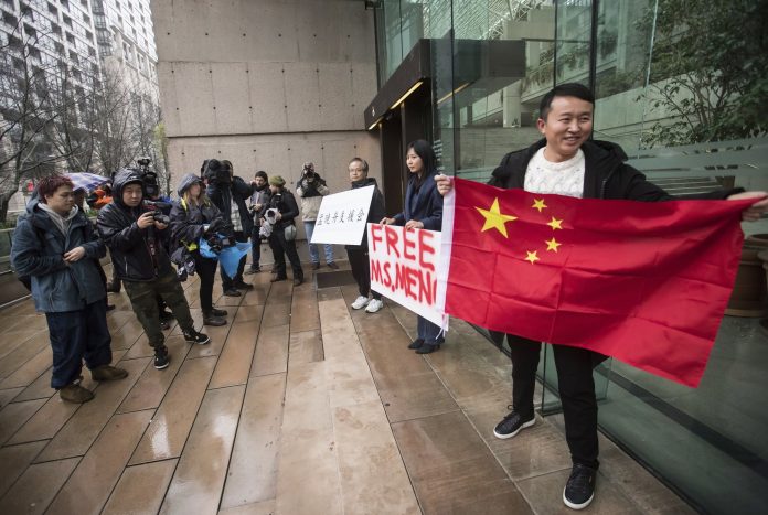 Supporters hold signs and a Chinese flag outside the British Columbia Supreme Court in Vancouver during the third day of a bail hearing for Meng Wanzhou, the chief financial officer of Huawei Technologies, on Dec. 11, 2018. (Darryl Dyck/The Canadian Press via AP)