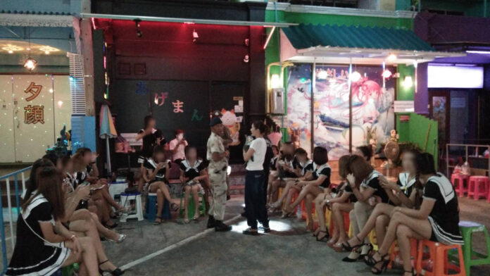 Suspected sex workers waiting outside while the police raided a bar in Si Racha, Chonburi on Aug. 15.