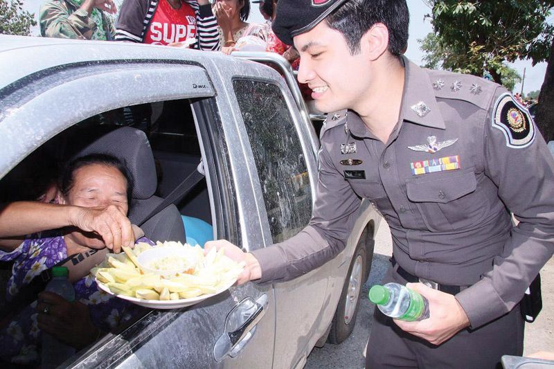 A police officer giving away free mango at a traffic checkpoint in Nakhon Sawan province, 15 April 2012.<br />