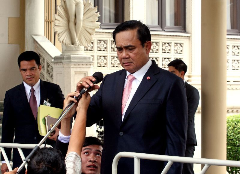 A journalist helps adjust Gen. Prayuth Chan-ocha's microphone during a press conference at the Government House, 25 June 2015.