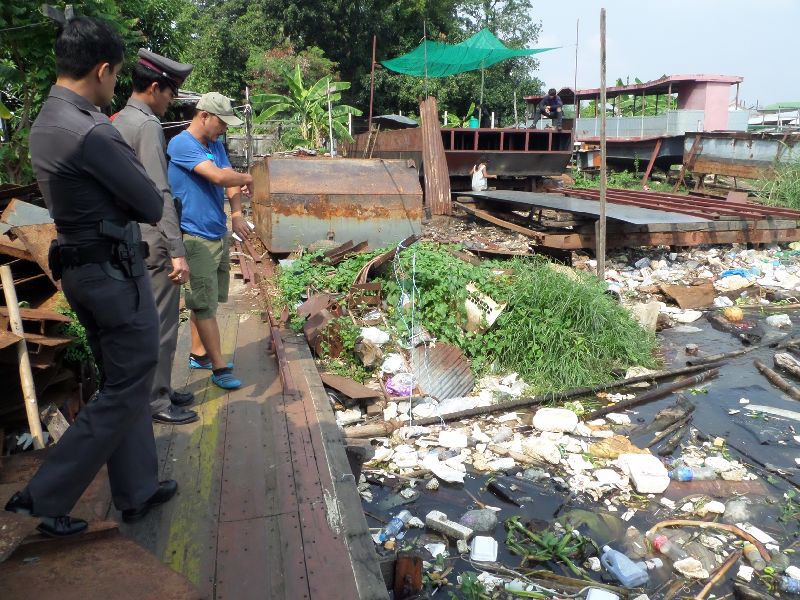 Police officers inspect a boat pier Saturday in Bangkok’s Bang Phlat district where a human arm washed up.