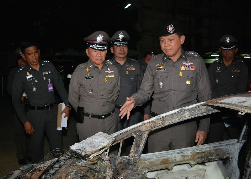 National police deputy commander Pongsapat Pongcharoen, at right, on Thursday night inspects the burned out remains of Ford Fiesta in the Sunday collision.