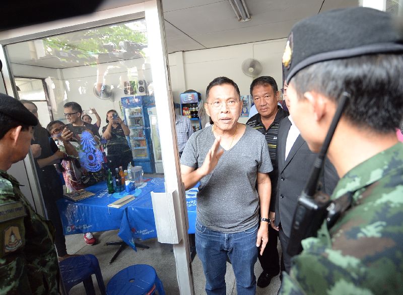 Watana Muangsook greets soldiers as he surrenders to the military on Monday at the 11th Army Circle headquarters in Bangkok.