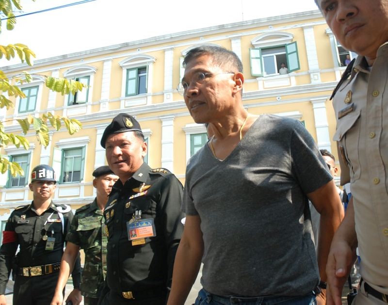 Watana Muangsook, who served in the former Pheu Thai led government, is escorted into the military court Thursday in Bangkok