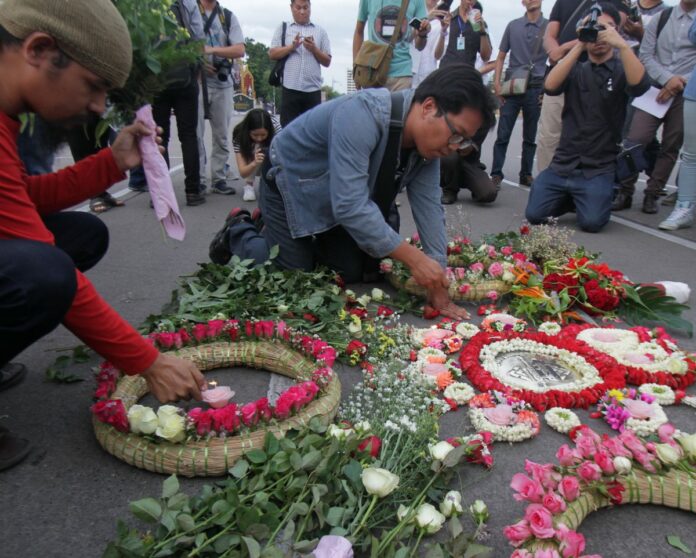 Activists place flowers and garlands around a small plaque memorializing the 1932 Revolution on June 24, 2015 in Bangkok.