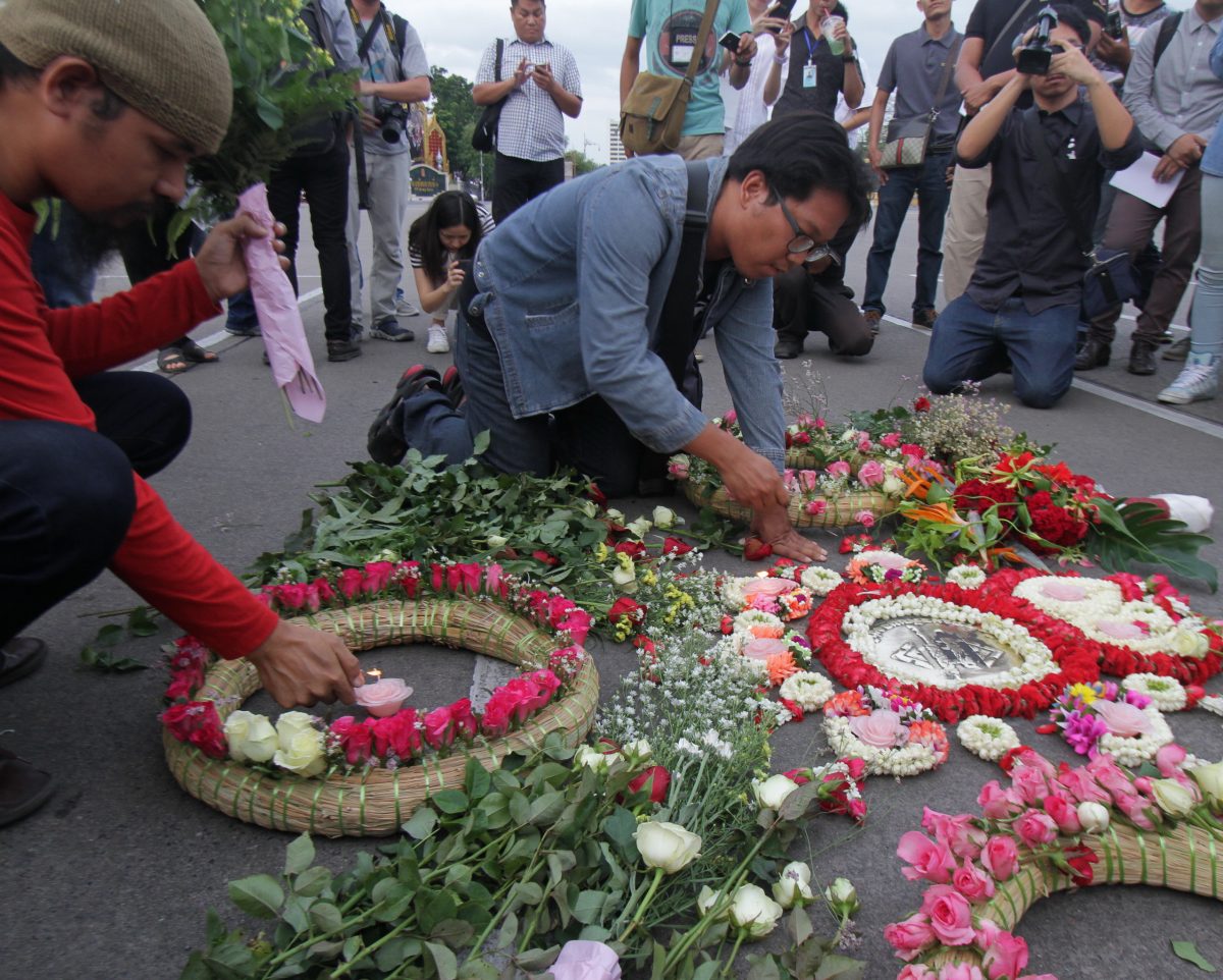 Activists place flowers and garlands around a small plaque memorializing the 1932 Revolution on June 24, 2015 in Bangkok.