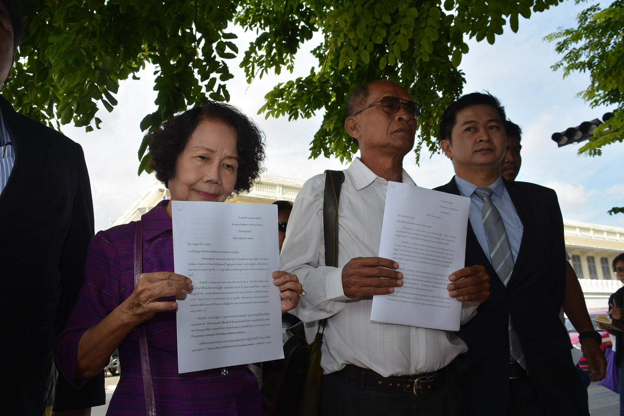 Arporn Worathaiwit, Krit Mahaton and lawyer Winyat Chartmontree show the petition they will submit Friday in front of the Office of His Majesty's Principal Private Secretary in Bangkok.