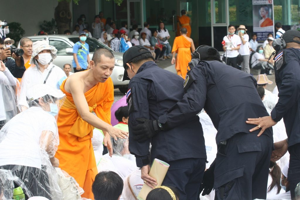 Armed with a search warrant in an envelope, DSI officers enter Wat Dhammakaya on Thursday to look for its fugitive abbot.
