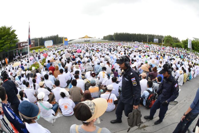 DSI officers walk past crowds of meditating worshipers during Thursday’s raid on Dhammakaya Temple in northern Bangkok.