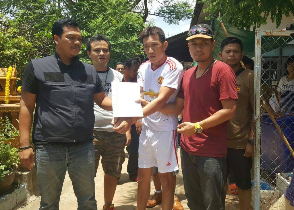 Police serve an arrest warrant to Udomsap Lomkaew, in white, Sunday in Korat