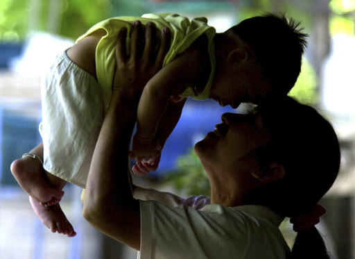 In this June 17, 2004, file photo, an HIV-positive mother plays with her son, who did not contract the virus from her, in Phetchaburi province, south of Bangkok. Photo: Sakchai Lalit / Associated Press