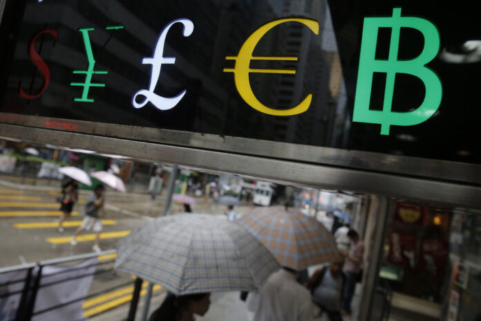 The currency signs of the Japanese Yen, English pound, euro and Thai baht are displayed at a money exchange shop Tuesday in Hong Kong. Photo: Kin Cheung / Associated Press