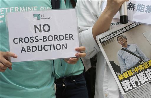 Members of pro-democracy group Demosisto, Joshua Wong, left, and Oscar Lai, hold the placards and newspaper with picture of Hong Kong bookseller Lam Wing-Kee during a protest in Hong Kong, Friday, June 17, 2016, as they march to the Chinese central government's liaison office. Photo: Kin Cheung / Associated Press