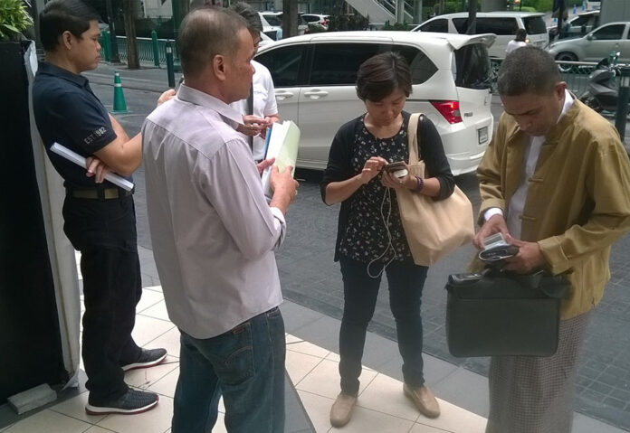 Rohingya activist and longtime resident of Thailand Hajee Ismail, far right, was told by undercover officers at left to leave the scene of an interview with reporters Thursday in Bangkok.