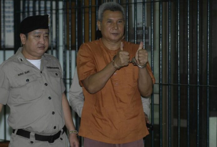 Thanat Thanawatcharanon raises two thumbs up to reporters Wednesday at the Criminal Court in Bangkok.