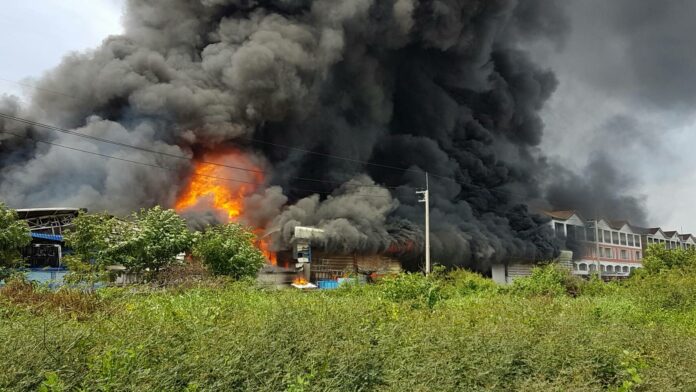 Smoke fills the afternoon sky Tuesday from a fire burning out of control at a factory near Talad Thai in Pathum Thani province.