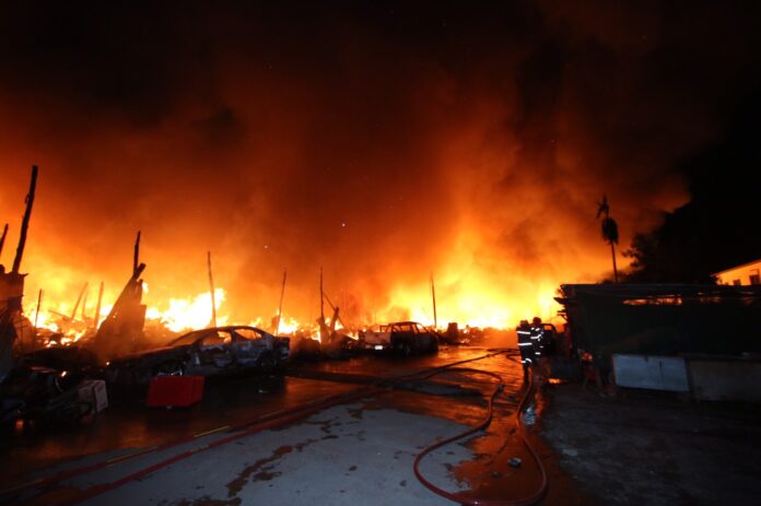 Cars burn as fire strikes a workers camp in Bangkok’s Don Muang district Wednesday evening.