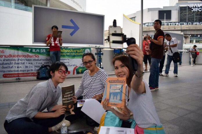 'Vote No' campaigners pause to take a selfie during a sit-in on Saturday on the skywalk near BTS National Stadium in Bangkok. Photo: Matichon