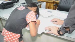 One of the schoolgirls signs a report Monday at the Khanu Woralaksaburi Police Station in Kampheng Phet province.