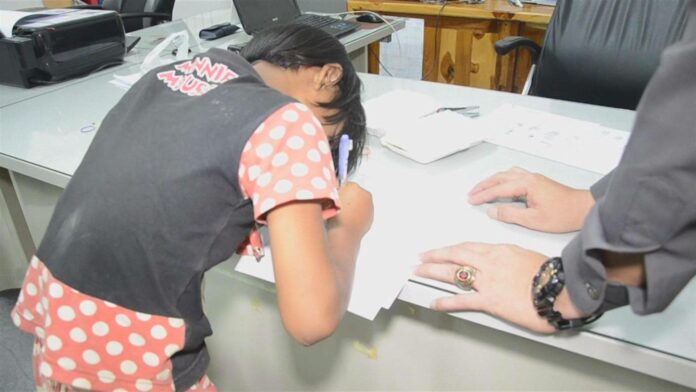 One of the schoolgirls signs a report July 18 at the Khanu Woralaksaburi Police Station in Kampheng Phet province.