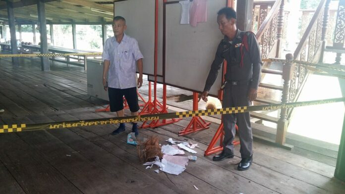 A Pichit police officer points to the devastation of referendum documents left behind by a rampaging pack of macaque monkeys Sunday at a local temple.