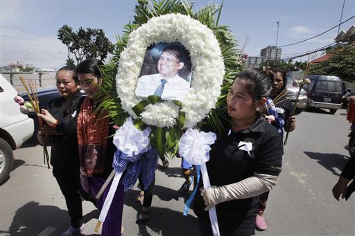 In this July 11, 2016 file photo, Cambodian community activists carry a wreath during the funeral procession of government critic Kem Ley, pictured, in Phnom Penh, Cambodia. Photo: Heng Sinith / Associated Press