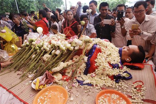 The body of Cambodian government critic Kem Ley is covered by the Cambodian National flag as flowers are placed during a funeral ceremony in Phnom Penh, Cambodia, Monday, July 11, 2016. Photo: Heng Smith / Associated Press