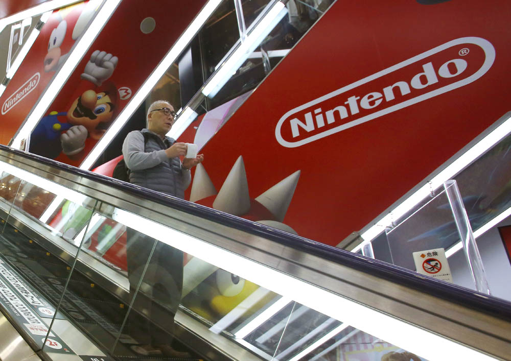 A shopper stands on an escalator March 20 in an electronics store in Tokyo. Photo: Shizuo Kambayashi / Associated Press