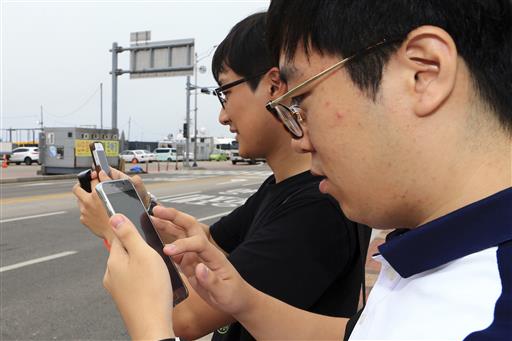 In this July 13, 2016 photo, two South Koreans play the Pokemon Go game with their mobile phones in Sokcho, South Korea. Photo: Lee Jong-hun / Yonhap / Associated Press